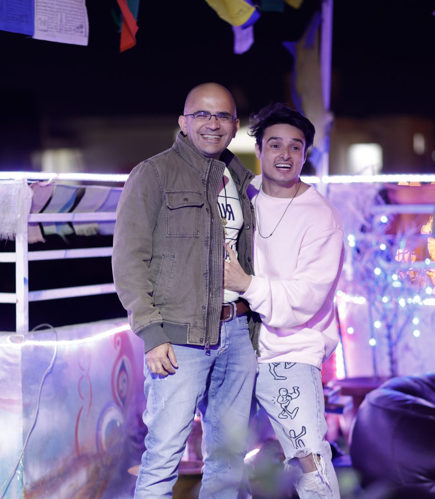 Dr. Maruti Sharma and Arun Sharma standing together at an evening event under prayer flags and festival lights