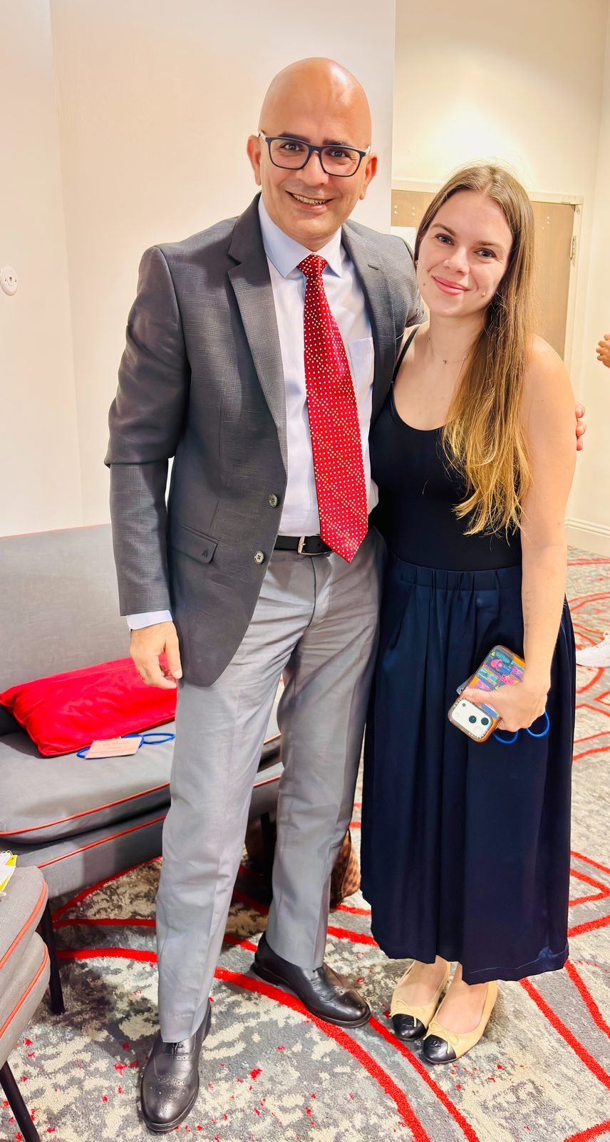 Dr. Maruti Sharma in a grey suit and red tie standing with Polina Maw, 2026